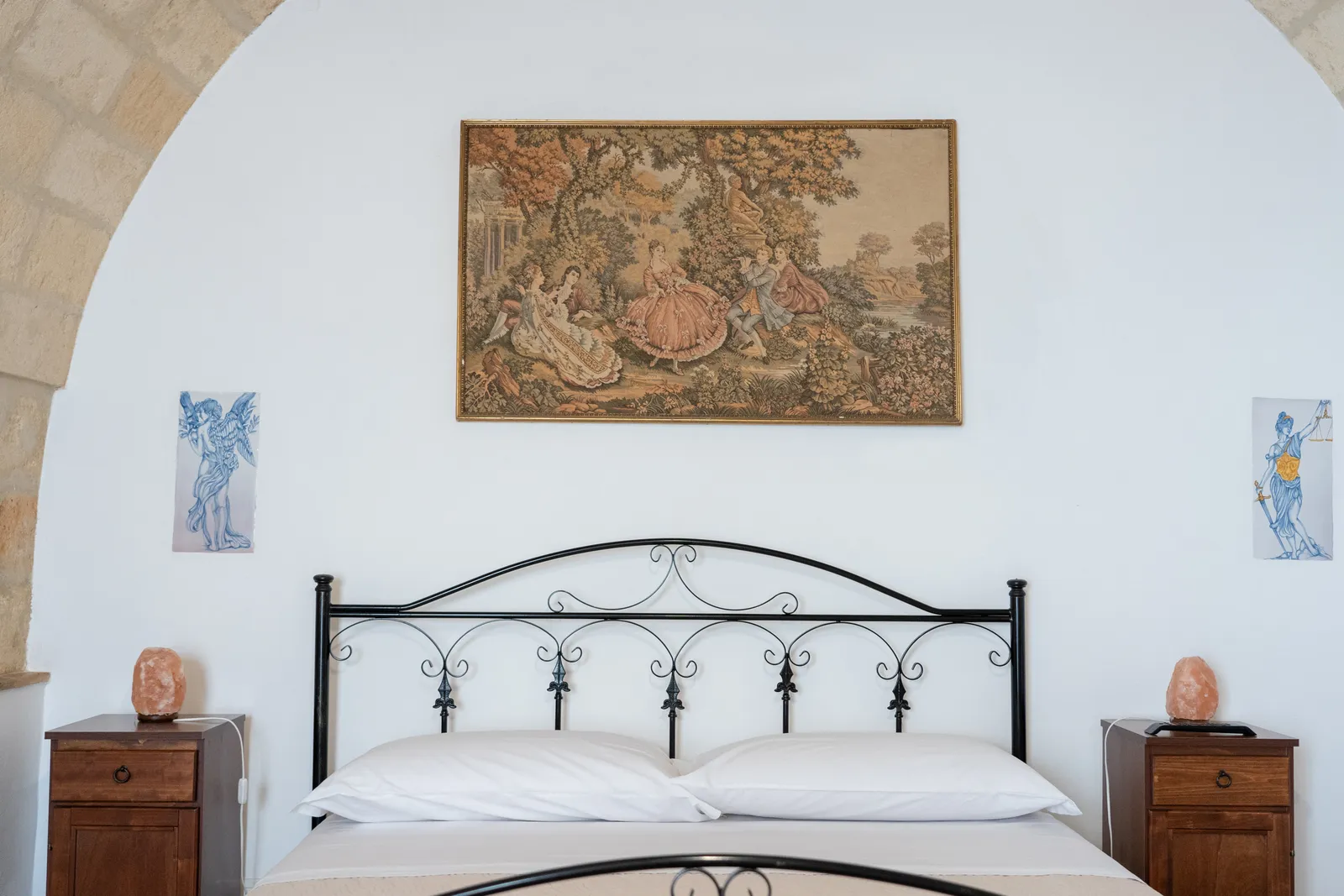Camera matrimoniale con letto in ferro battuto e arazzo
